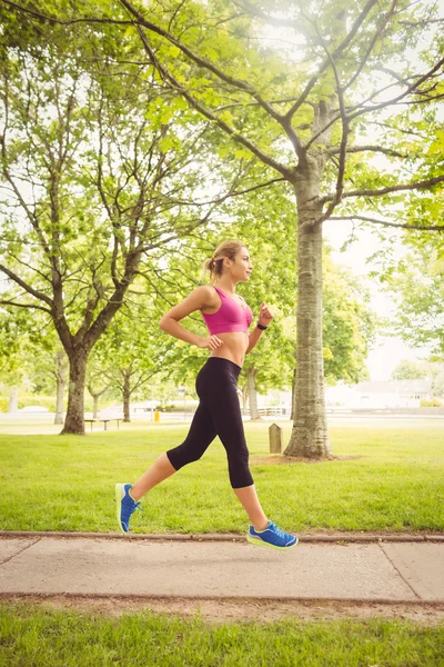 Sidovy av sportiga kvinnan jogging i park — Stockfoto