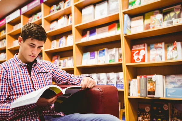 Concentrato giovane uomo lettura libro in biblioteca — Foto Stock