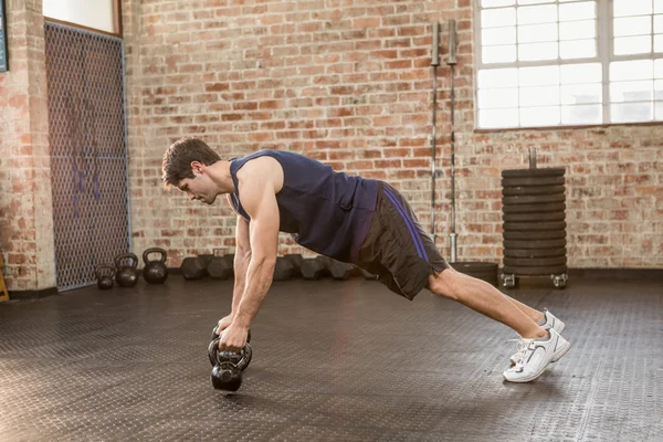 Hombre haciendo push up sosteniendo kettlebell —  Fotos de Stock