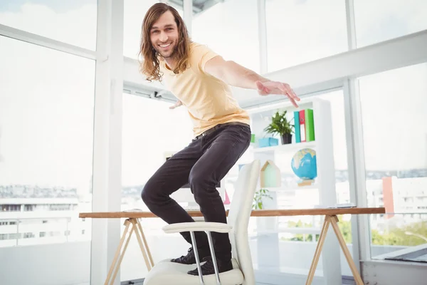 Joyeux hipster debout sur la chaise dans le bureau — Photo