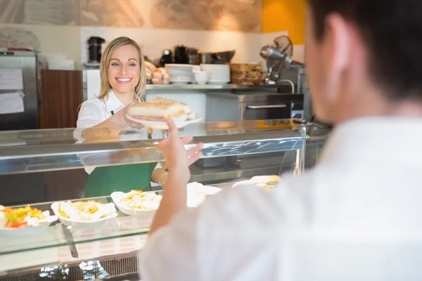 Femme propriétaire de magasin donnant sandwich au client — Photo