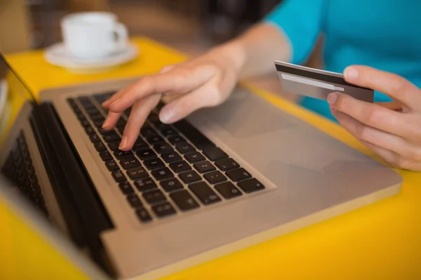 Woman using laptop while holding credit card — Stock Photo, Image