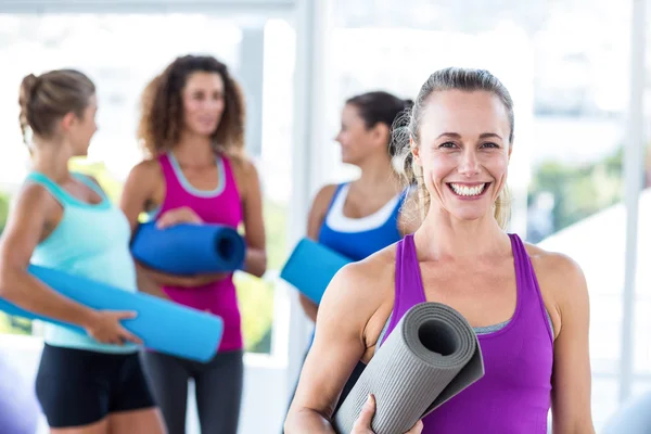 Portrait of cheerful woman holding exercise mat and smiling — Stock Photo, Image