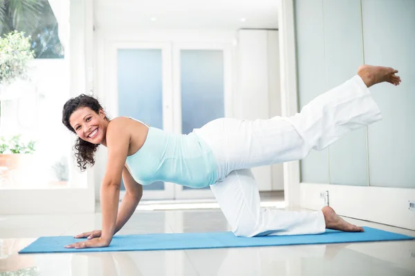 Mujer embarazada sonriente realizando yoga en la estera —  Fotos de Stock