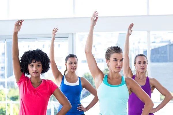 Focused woman in fitness studio with left arm raised — Stock Photo, Image