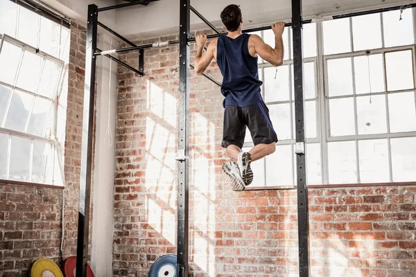 Rear view of muscular man doing pull ups — Stock Photo, Image