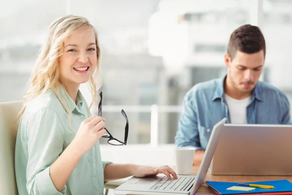 Retrato de mulher feliz segurando óculos no escritório — Fotografia de Stock