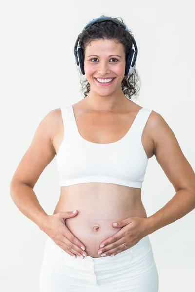 Mujer embarazada sonriente escuchando música — Foto de Stock