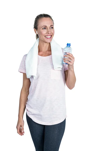 Happy sporty woman holding bottle while listening music — Stock Photo, Image