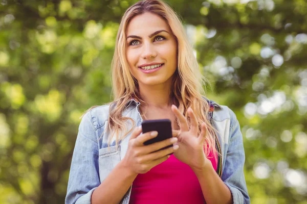 Donna sorridente guardando lontano mentre tocca smartphone — Foto Stock