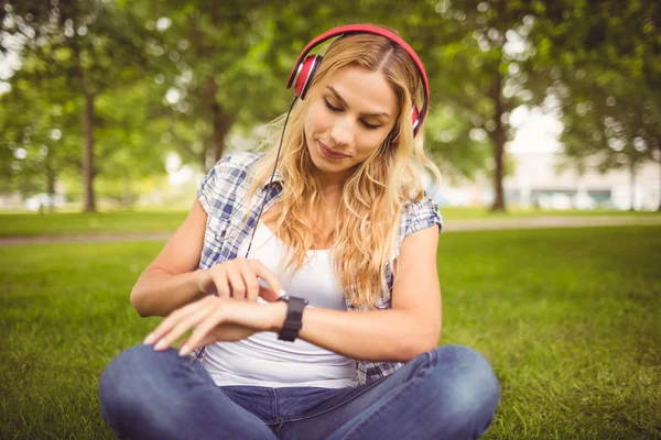 Kobieta, słuchanie muzyki i przy użyciu pokładzie smartwatch w parku — Zdjęcie stockowe