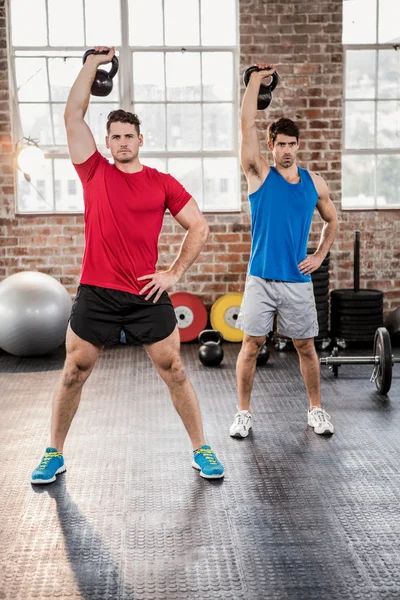 Muscular men lifting kettlebell — Stock Photo, Image