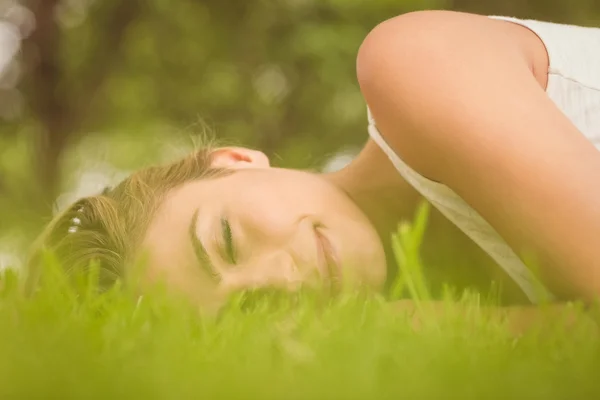 Piękna kobieta z oczy zamknięte leżąc na trawie — Zdjęcie stockowe