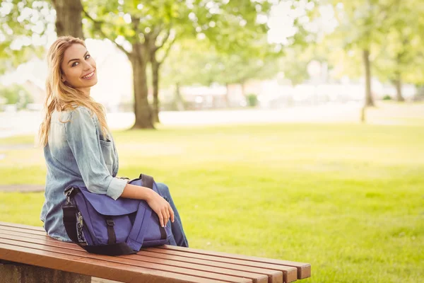 Портрет улыбающейся женщины на скамейке в парке — стоковое фото