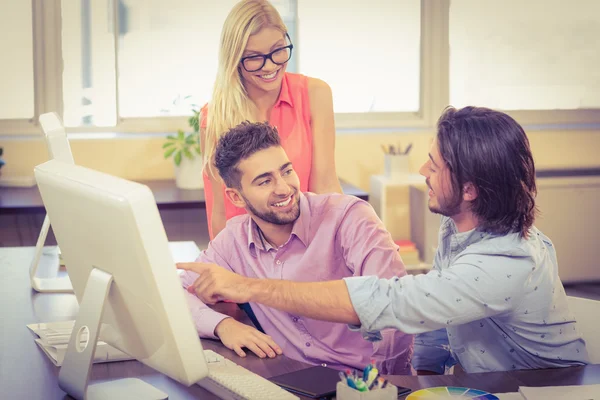 Empresario apuntando a la computadora como colegas sonrientes buscando un —  Fotos de Stock