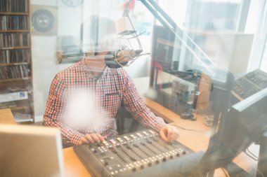 Radio host operating sound mixer in studio clipart