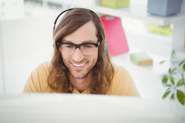 Joyeux hipster portant des écouteurs au bureau — Photo