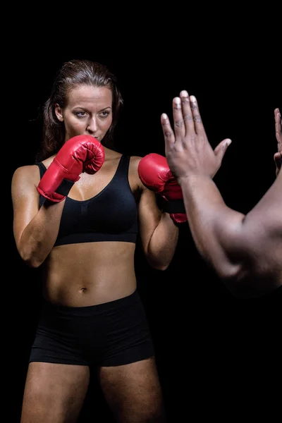Vrouwelijke bokser met vechten houding tegen trainer hand — Stockfoto