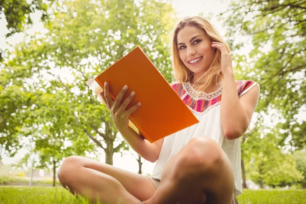 Низкоугольный портрет улыбающейся женщины с книгой в руках — стоковое фото