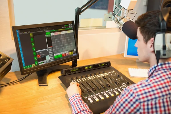 Rádio host operando misturador de som enquanto procura no monitor — Fotografia de Stock