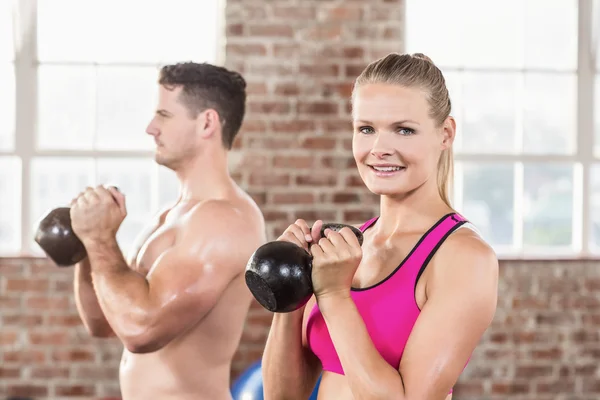Muscular smiling couple with kettlebells — Stock Photo, Image