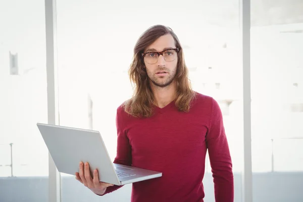 Ritratto di hipster che tiene il computer portatile contro la finestra — Foto Stock