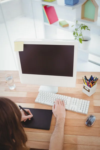 Hipster with graphics tablet working at computer desk — Stock Photo, Image