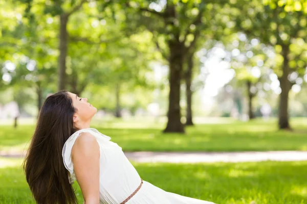 Boční pohled na hnědé vlasy ženu sedící na trávě — Stock fotografie