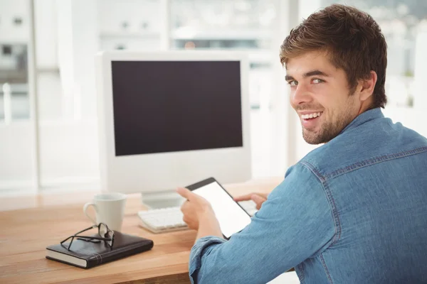 Homme d'affaires heureux utilisant une tablette numérique tout en étant assis au bureau — Photo