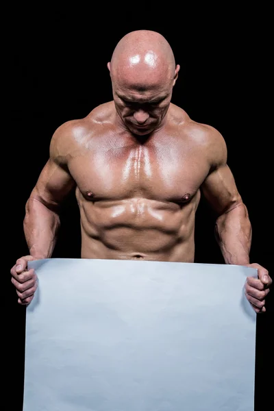 Homem muscular segurando papel em branco — Fotografia de Stock