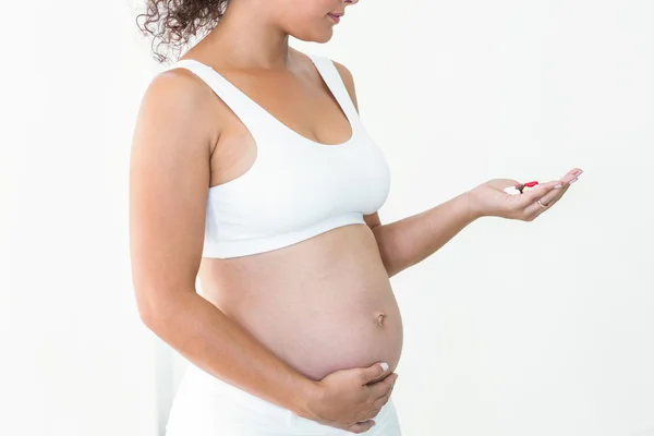 Mulher grávida segurando pílulas — Fotografia de Stock