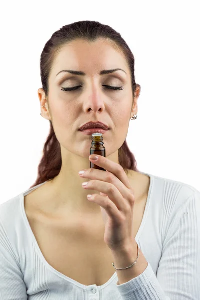 Woman with eyes closed and smelling bottle of medicine — Stock Photo, Image