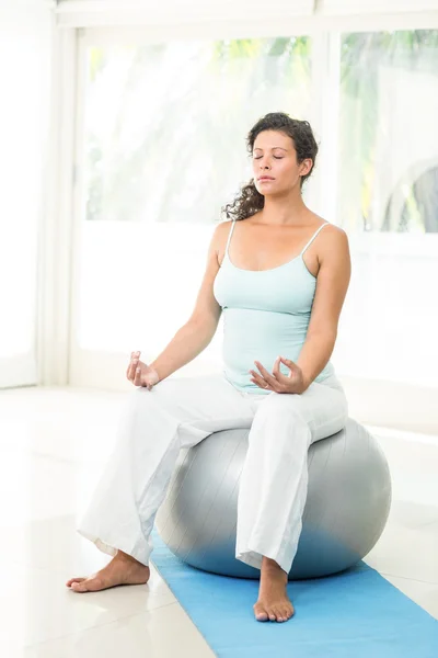 Mulher grávida loira pacífica sentada na bola de exercício — Fotografia de Stock
