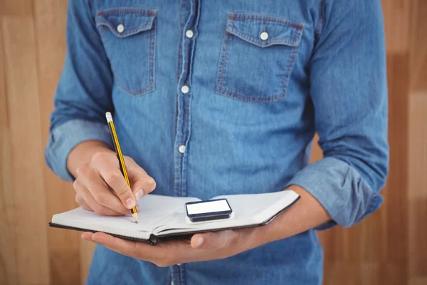 Mid section of man writing with pencil on book — Stock Photo, Image