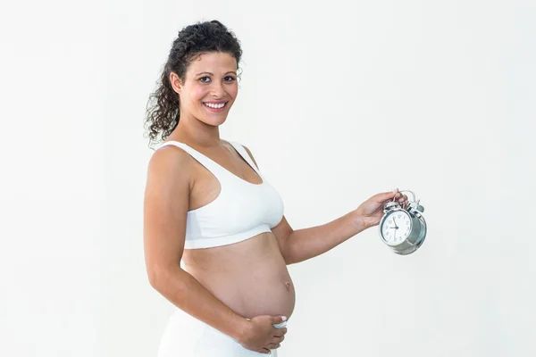 Sorrindo mulher grávida segurando despertador — Fotografia de Stock