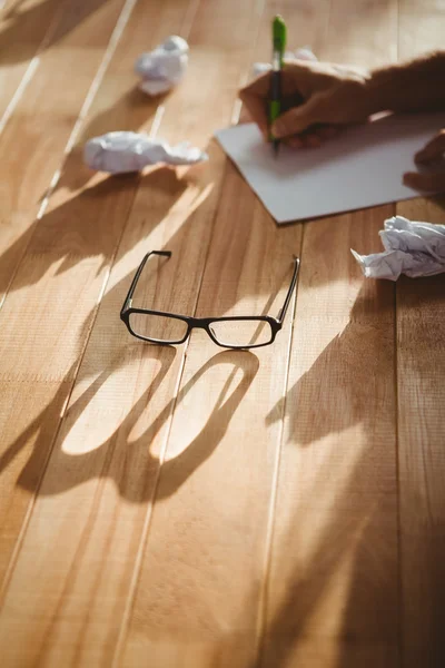 Óculos de olho por homem escrevendo na mesa no escritório — Fotografia de Stock