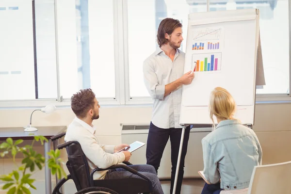 Uomo d'affari che spiega il grafico multicolore ai colleghi — Foto Stock