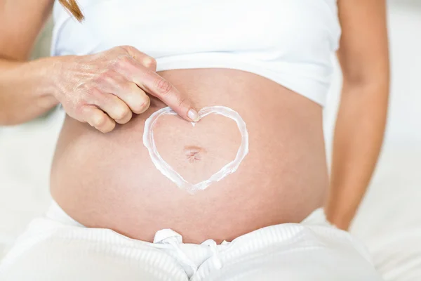 Vientre embarazada con loción para el corazón —  Fotos de Stock