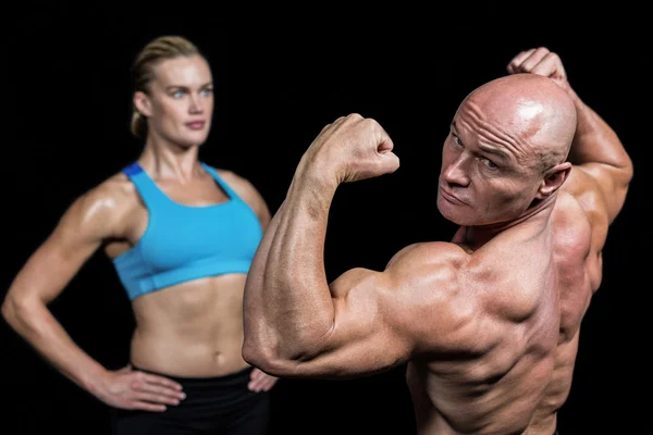 Muscular man flexing muscles in front of instructor — Stock Photo, Image