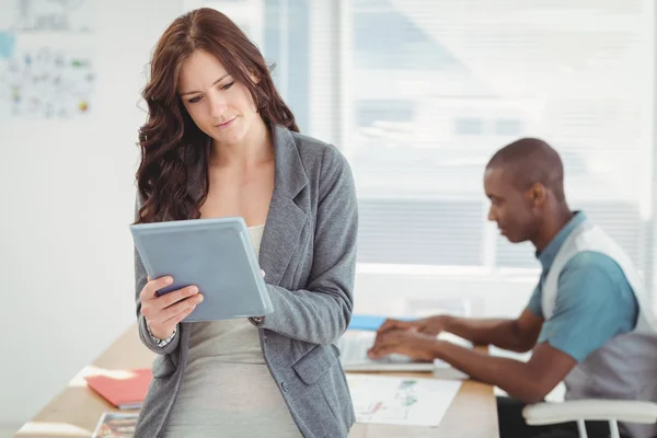 Mujer usando tableta digital con el hombre trabajando en el escritorio — Foto de Stock