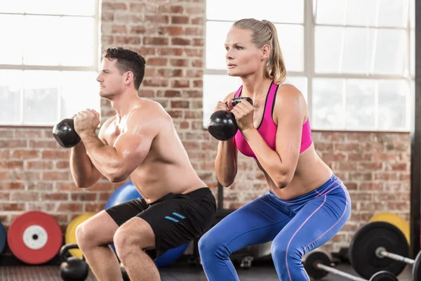 Muskulöses ernsthaftes Paar mit Kettlebells — Stockfoto