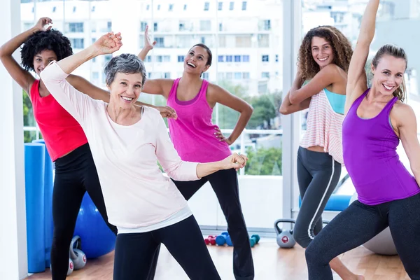 Fröhliche Frauen, die mit erhobenen Armen üben — Stockfoto