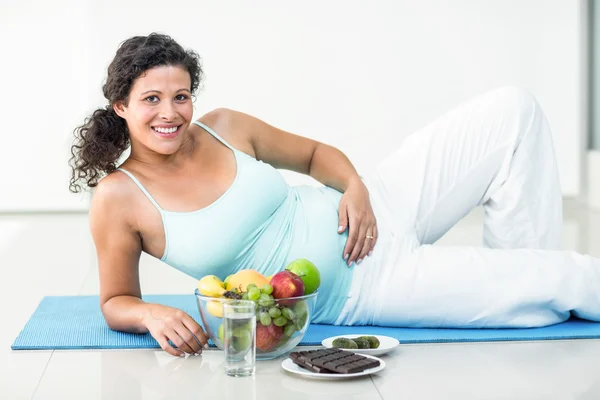 Retrato de mujer embarazada acostada por frutas y chocolates — Foto de Stock