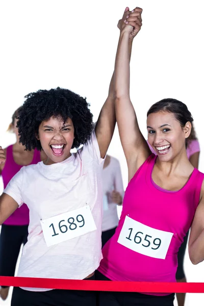 Portrait of cheerful winner athletes crossing finish line with a — Stock Photo, Image