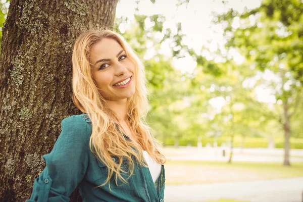 Retrato de una hermosa mujer sonriente de pie junto al árbol —  Fotos de Stock