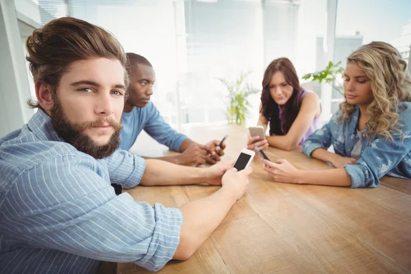 Retrato de hombre sosteniendo smartphone con compañeros de trabajo —  Fotos de Stock