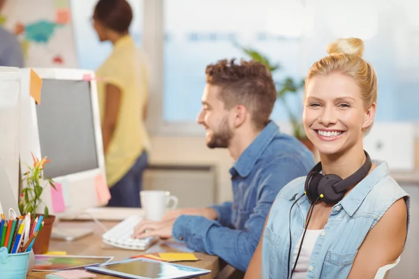 Femme d'affaires souriante assise contre les employés — Photo