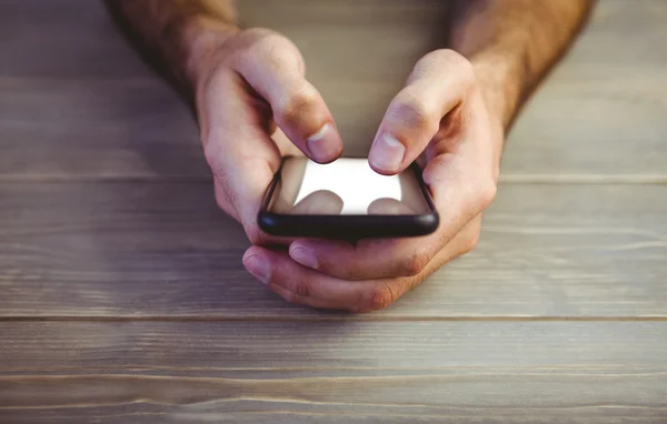 Person hält Smartphone am Holztisch — Stockfoto