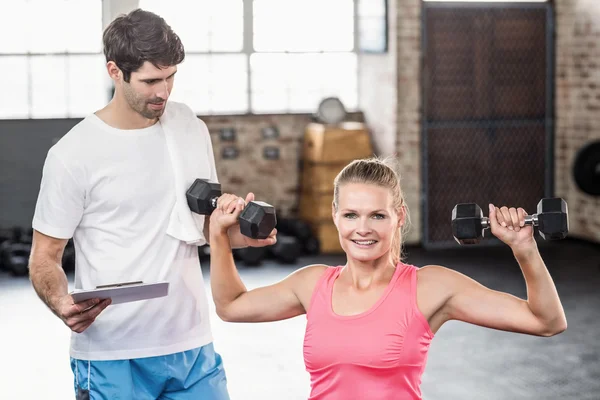 Passen vrouw opheffing halters met trainer — Stockfoto