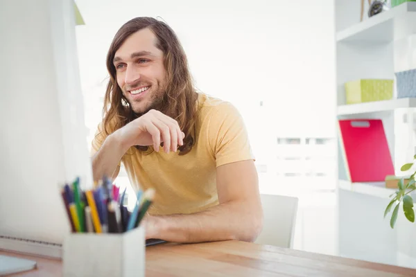 Hipster souriant tout en travaillant au bureau de l'ordinateur — Photo